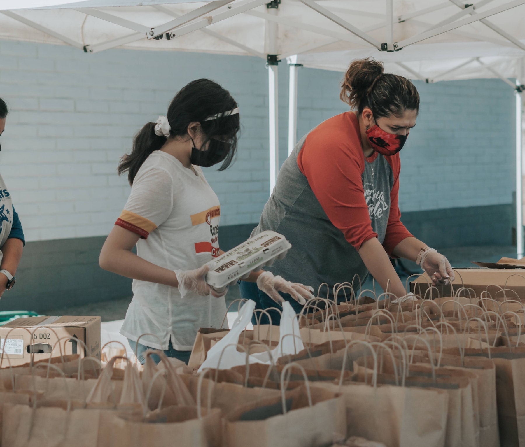 two volunteers preparing food parcels outdoors