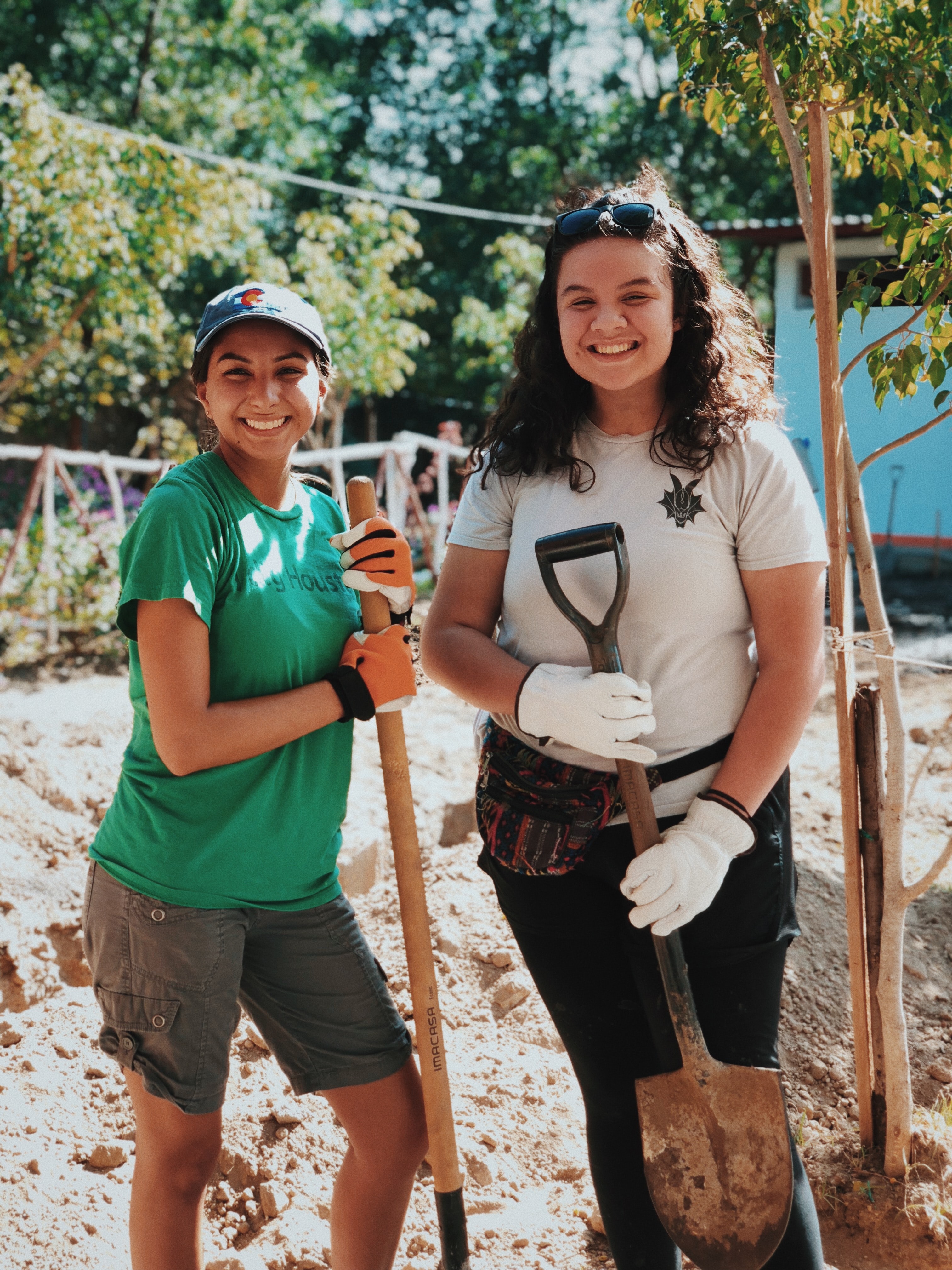 women volunteers gardening holding shovels and smiling 